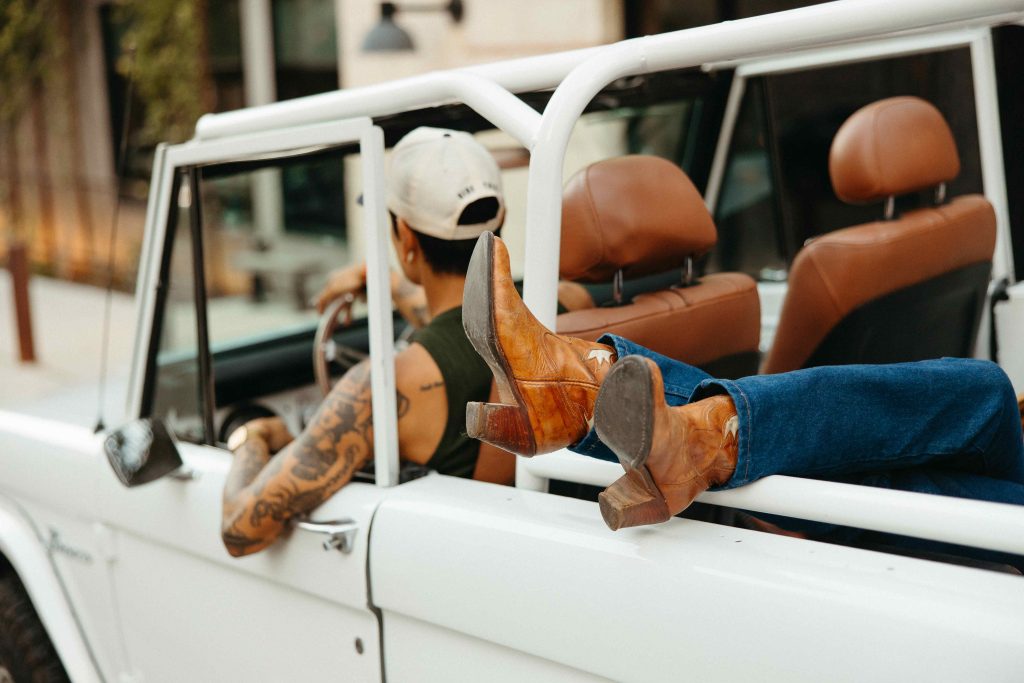Woman sitting in the back of a car with her feet hanging out of the window