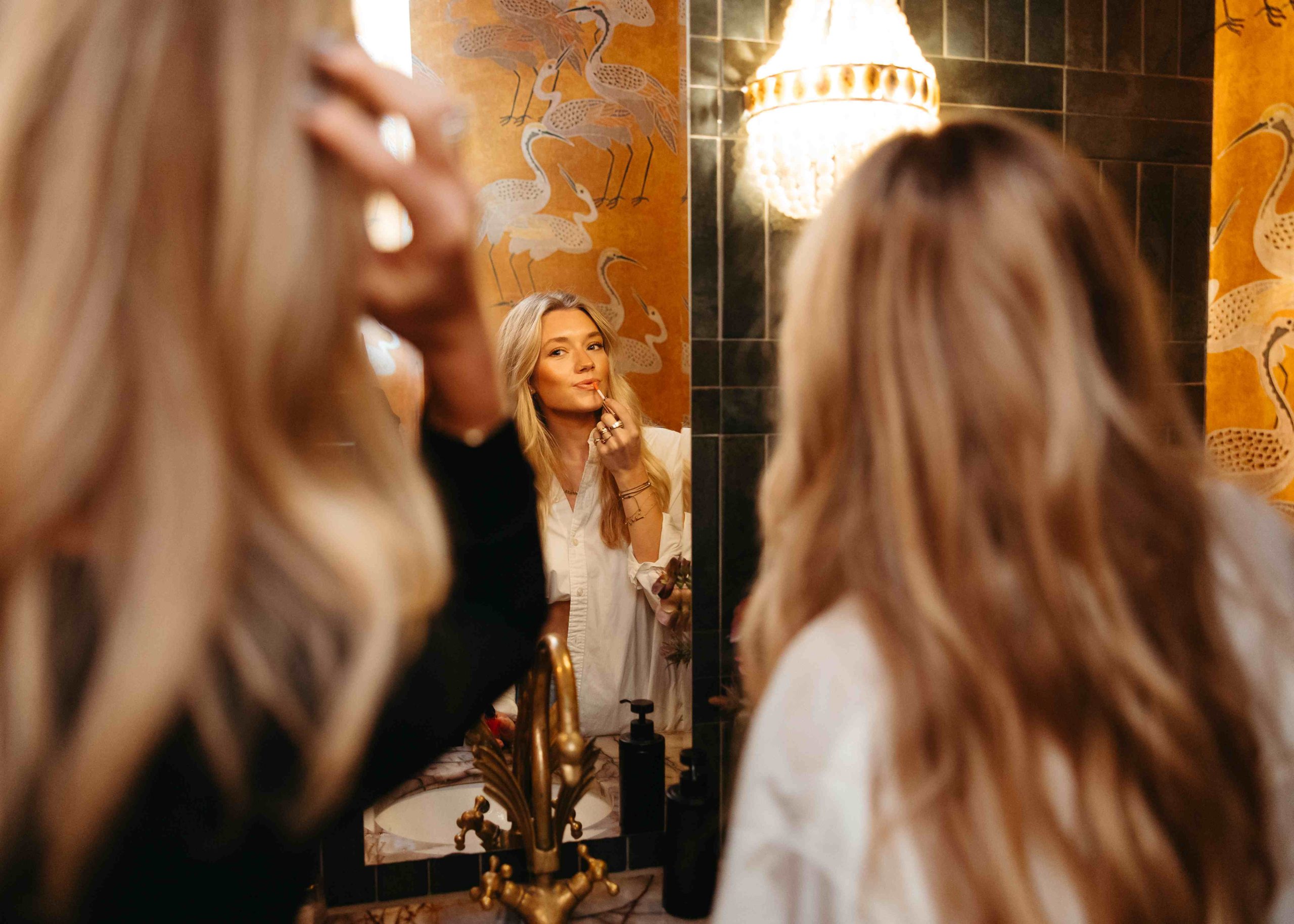 Woman applying lipstick in a mirror