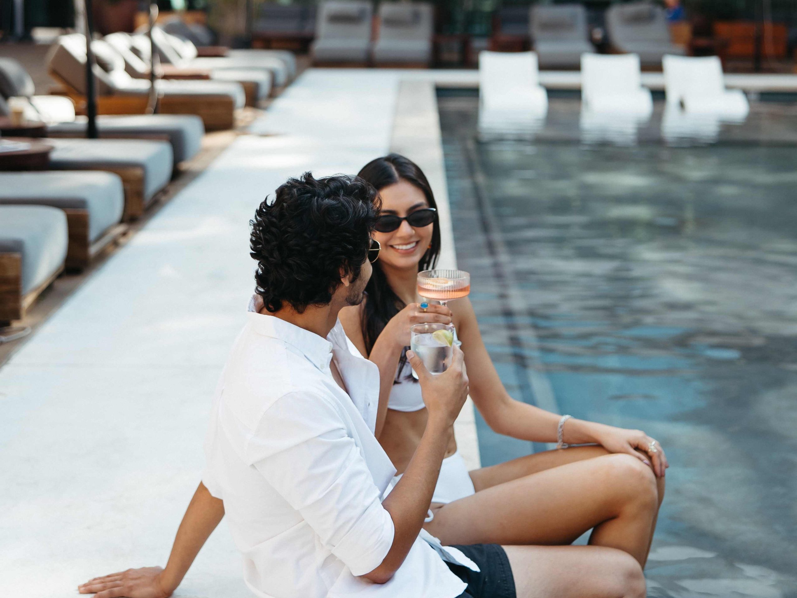 Two people sitting at the edge of a pool