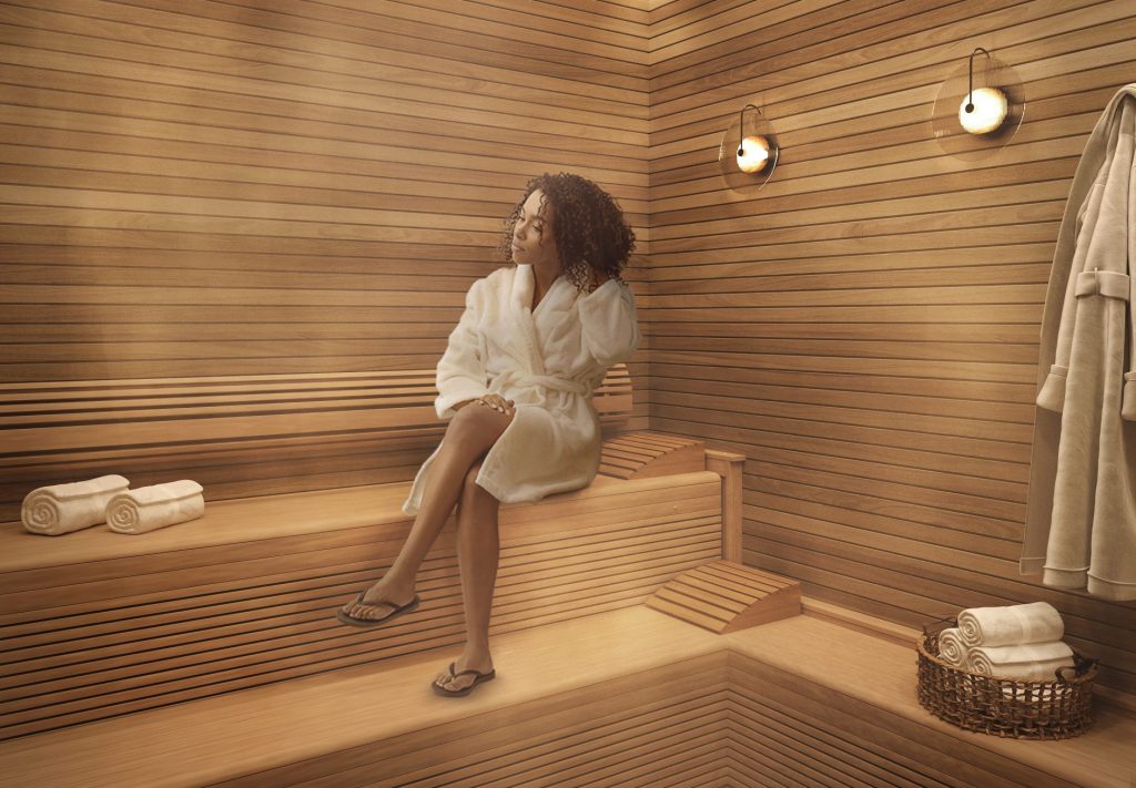Woman relaxing in sauna, alongside towels and moody lighting, at Paseo in downtown Austin.