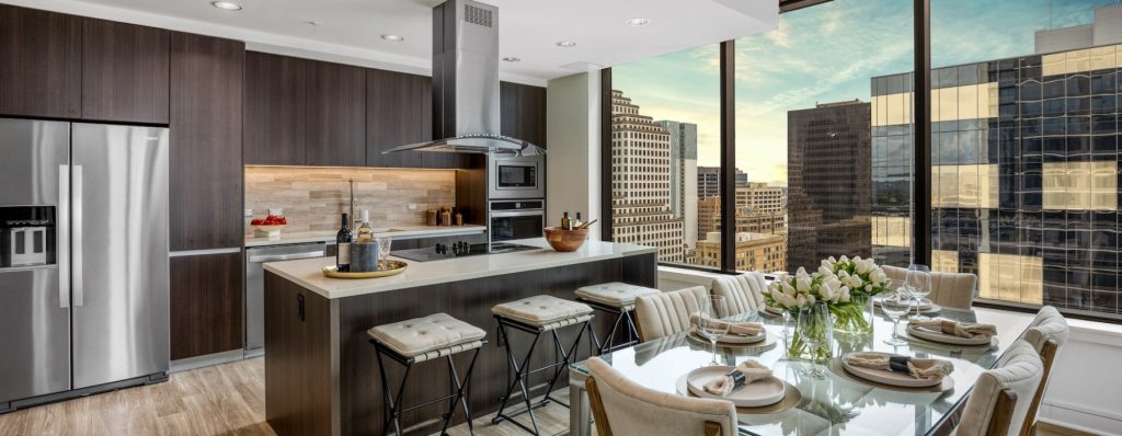Modern apartment kitchen with wood cabinetry, stainless steel appliances at Hanover Republic Square, a luxury apartment located in downtown Austin, Texas.