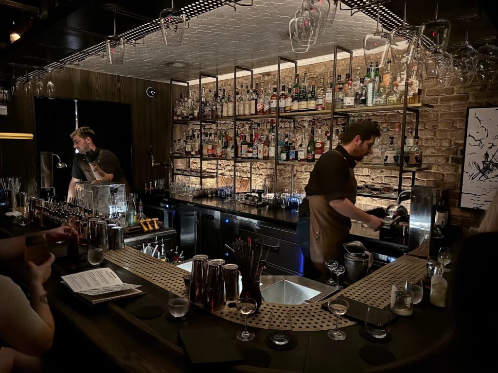 Intimate speakeasy cocktail bar in downtown Austin with moody lighting and bartenders mixing drinks.