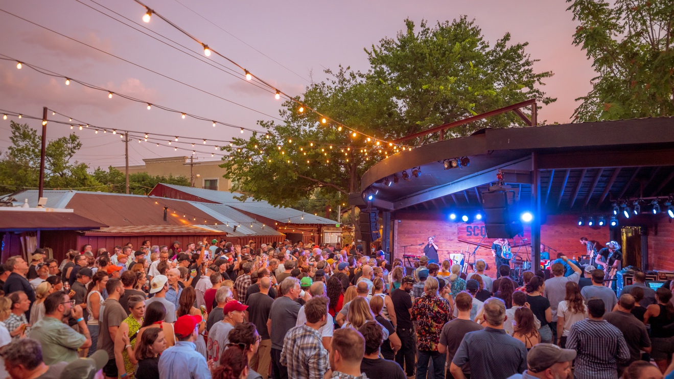 Outdoor stage at the Historic Scoot Inn in Austin with the audience enjoying a live music show.