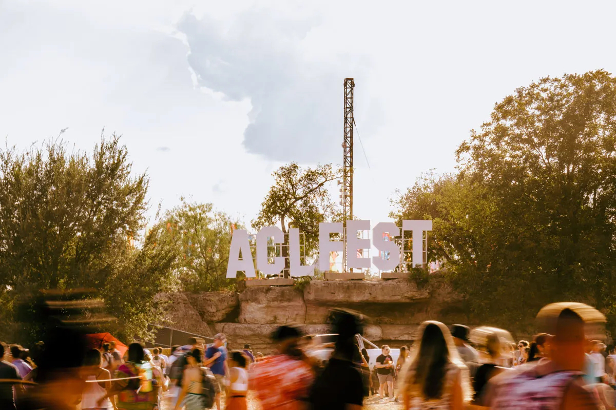 Festival crowd walking past the ACL Fest sign at Zilker Park.