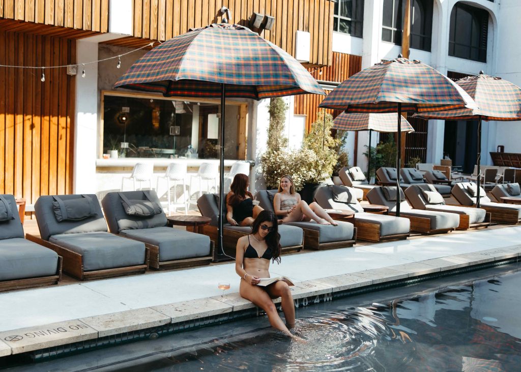 Women relaxing on lounge chairs and by the pool at a modern apartment complex.