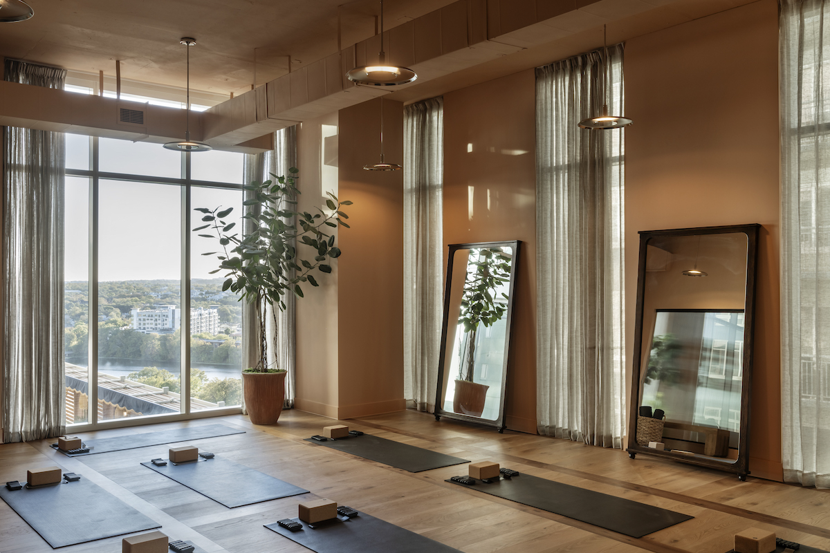 Warm-lit yoga room overlooking Lady Bird Lake at Paseo In Downtown Austin.