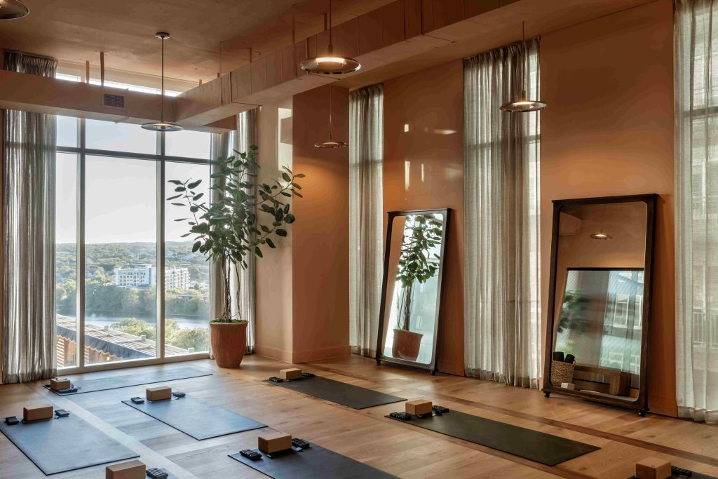 Warm-lit yoga room overlooking Lady Bird Lake at Paseo in downtown Austin.