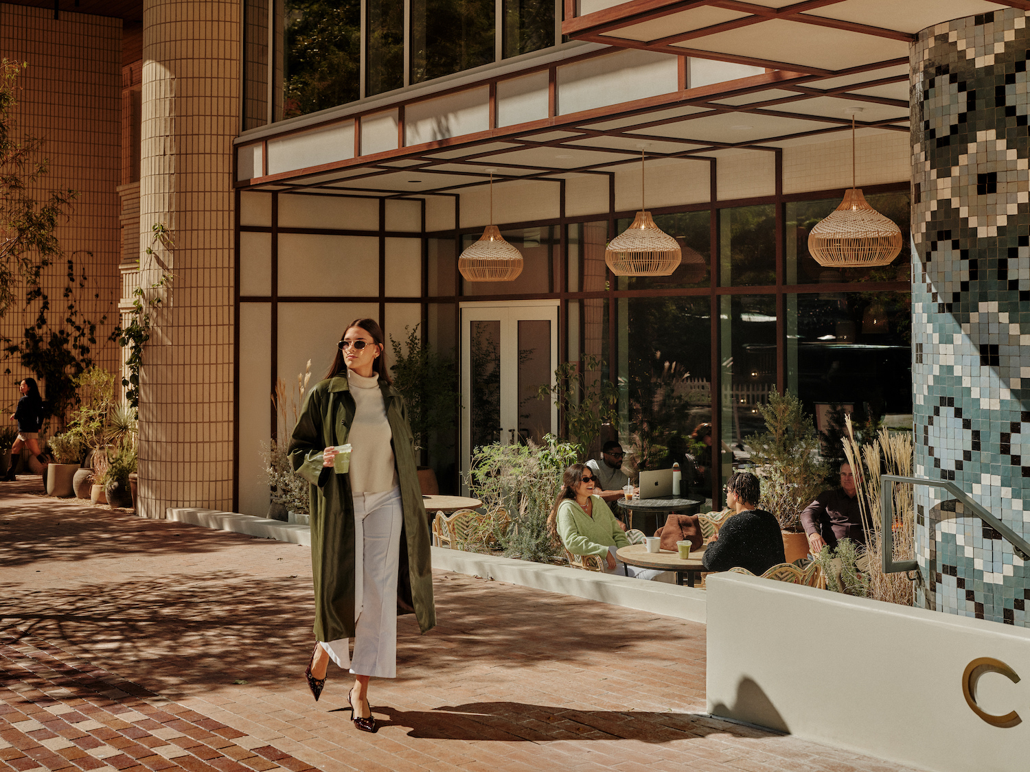 A woman strolls along a brick walkway, enjoying the elegant surroundings of luxury apartments in Austin, TX.